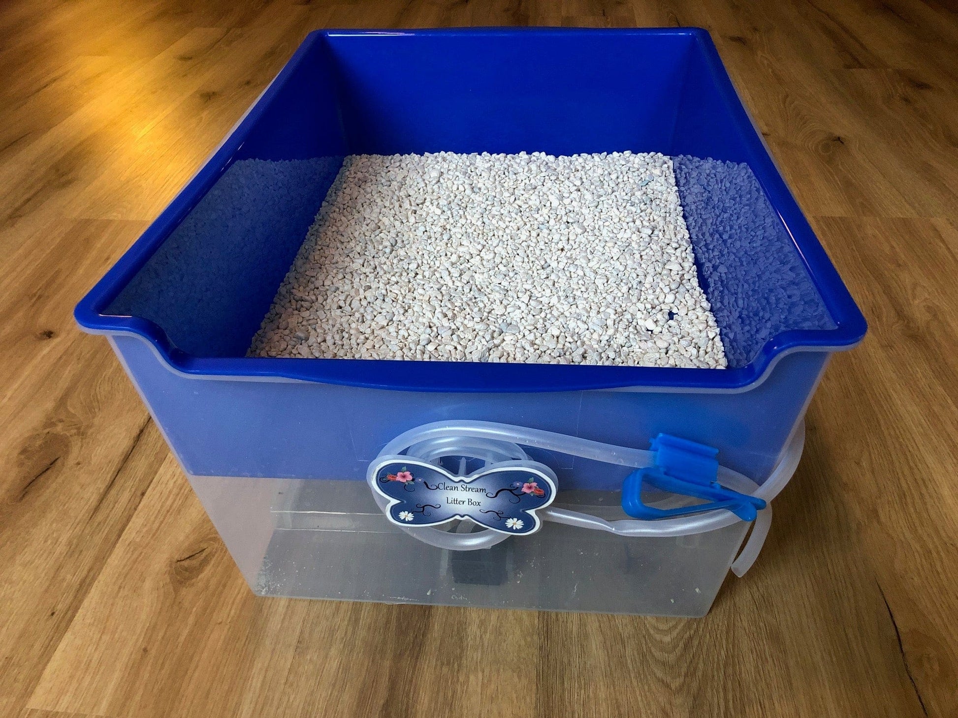 Eco-friendly Clean Stream Litter Box with fish tank gravel on wooden floor.